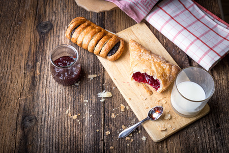 breakfast pastries with jam and milk on old wooden tableの写真素材