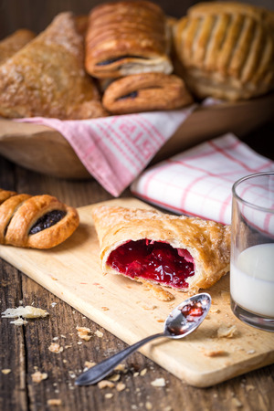 assorted breakfast pastries with jam and milk on old wooden tableの写真素材