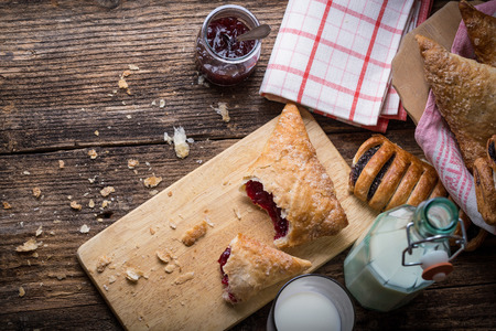 breakfast pastries with jam and milk on old wooden tableの写真素材