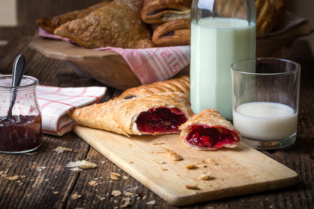 breakfast pastries with jam and milk on old wooden tableの写真素材