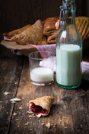 assorted breakfast pastries with jam and milk on old wooden tableの写真素材