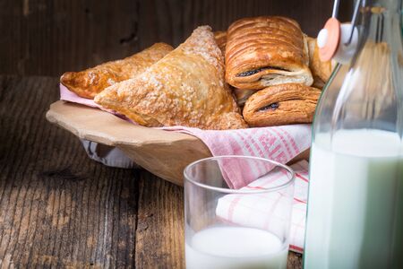 assorted breakfast pastries and milk on old wooden tableの写真素材