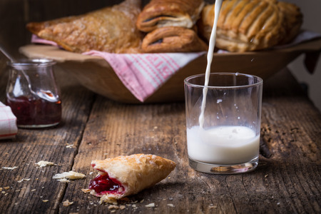 breakfast pastries with jam and milk on old wooden table, splash milkの写真素材
