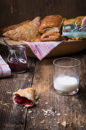 breakfast pastries with jam and milk on old wooden table, splash milkの写真素材