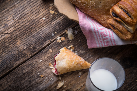 assorted breakfast pastries with jam and milk on old wooden tableの写真素材