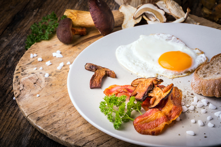 Egg with mushrooms and bacon on the plate with salt and pepper.の写真素材