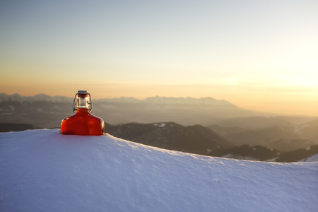 bottle of liquor zirbenschnaps in the snowy mountainsの写真素材