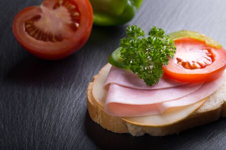 Bread or sandwich with ham, tomato and red pepper on black backgroundの写真素材
