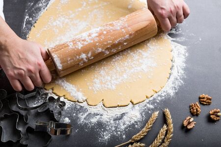 Rolling dough with wooden roller and flour  on the black backgroundの写真素材