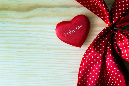 valentine heart with red dotted ribbon on a wooden backgroundの写真素材