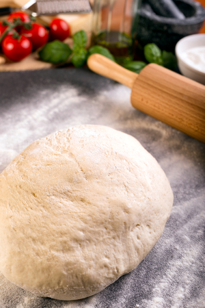 Prepering pizza dough with wooden roller, basil, olive oil and other ingredients.の写真素材