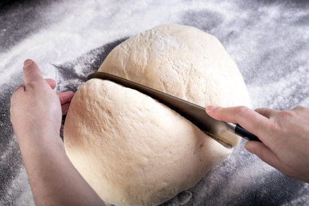 Cutting dough with knife on small portion for pizza dough.