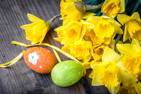 Bunch of daffodils on the wooden background with easter eggs for Easterの写真素材