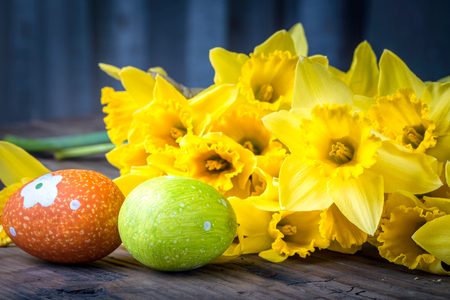 Bunch of daffodils on the wooden background with easter eggs for Easterの写真素材