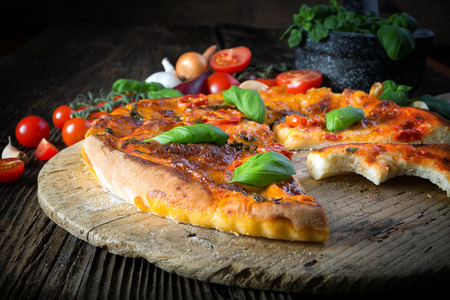 homemade pizza margherita with mozzarella, basil and tomatoes, bite offのeditorial素材