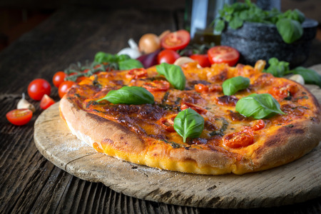 homemade pizza margherita with mozzarella, basil and tomatoes on a wooden boardの写真素材
