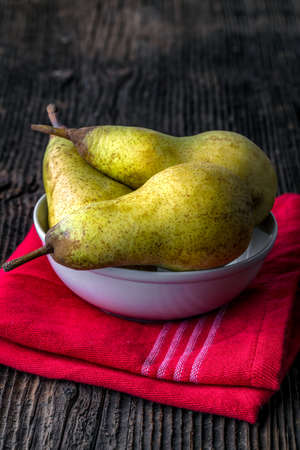 Fresh pears in a bowl on old wooden tableの写真素材