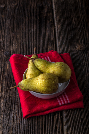 dewy fresh pears in a bowl on old wooden tableの写真素材
