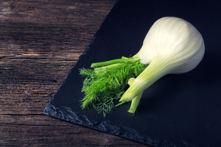 Fresh white fennel with green stem on the black plateの写真素材