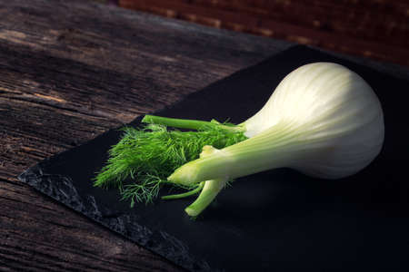 Fresh white fennel with green stem on the black plateの写真素材