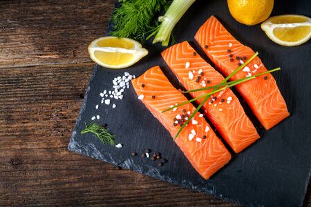 Salmon filet sliced on three parts  with lime, salt, pepper, rucoli,fennel and rosemary,  ready to cook.の写真素材