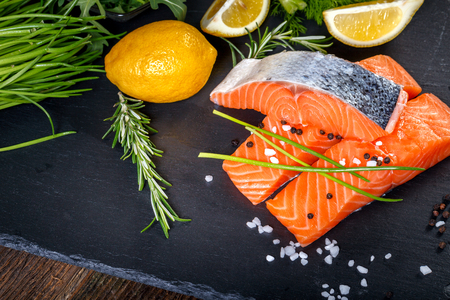 Salmon filet sliced on three parts  with lime, salt, pepper, rucoli,fennel and rosemary,  ready to cook.の写真素材