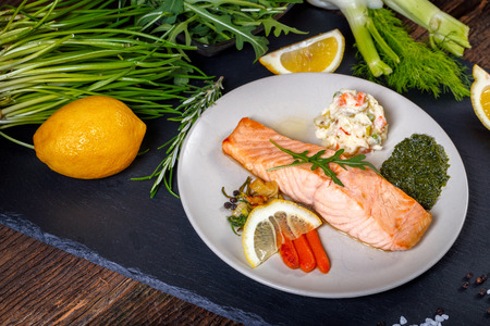 Grilled Salmon with lemon, herbs and pesto. Red carrots. Potato salad.の写真素材