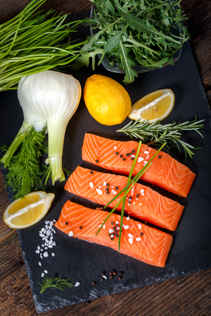 Salmon filet sliced on three parts  with lime, salt, pepper, rucoli,fennel and rosemary,  ready to cook.の写真素材