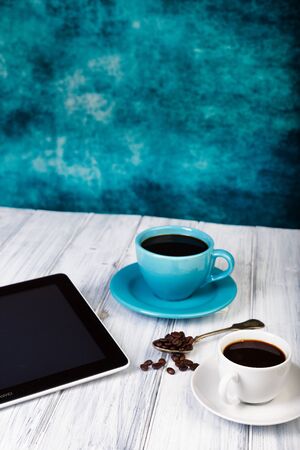 Coffee and tablet on the table. Pause and coffeetime. Blue cup and background.の写真素材