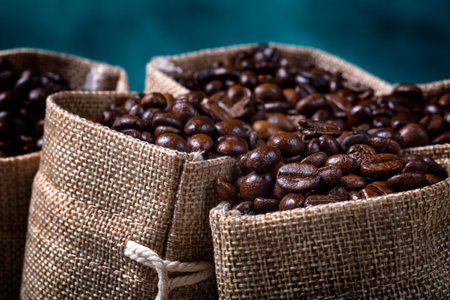Coffee seeds with some jute bags filled with coffee beans.