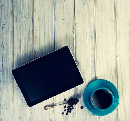 Coffee and tablet on the table. Pause and coffeetime. Blue cup and background.の写真素材