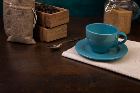 Empty cup of coffee and jute bags, wooden containers filled with cofee beans on the rust background. Cane sugar.の写真素材