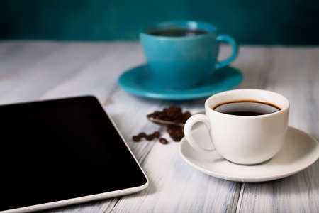 Coffee and tablet on the table. Pause and coffeetime. Blue cup and background.の写真素材