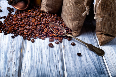 Coffee seeds in spoon with some jute bags filled with coffee beans.の写真素材