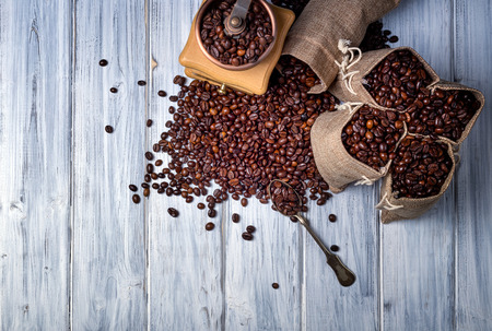 Coffee seeds in spoon with some jute bags filled with coffee and coffee grinderの写真素材