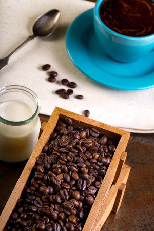 Cup of coffee and wooden containers filled with cofee beans on the rust background. Cane sugar. Low light.の写真素材