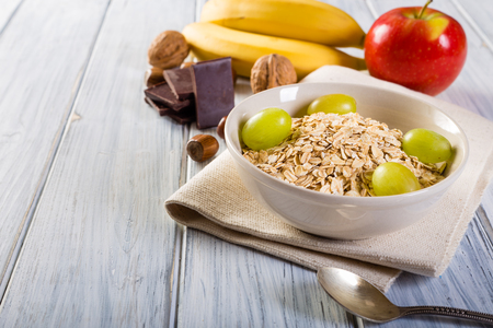 Oatmeal with apple, banana, grape chocolate. Bowl of fresh fruit.の写真素材