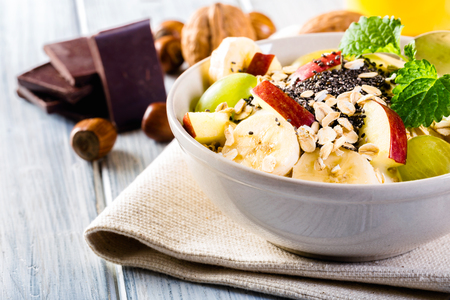 Oatmeal with yoghurt, apple, banana, grape and chia seeds. Bowl of fresh fruit.の写真素材