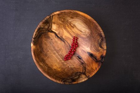 Bunch of red currants in a bowl from walnut wood. Healthy fruit with antioxidant.の写真素材