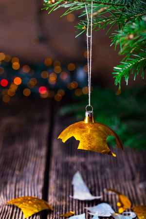 Broken old vintage Christmas ball on wooden table. Christmas lights and Christmas tree.の写真素材