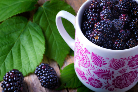 Cup of fresh natural blackberries with biscuits. Blackberries leaf on a wooden table.の写真素材