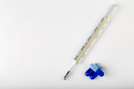 Bunch of blue pills with thermometer on the white background