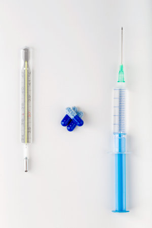 Syringe with bunch of blue pills and  thermometer