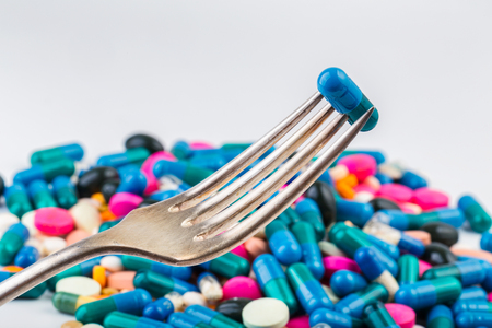 Tablet pierced on a fork. Tablets and pils. Scattered pills. Silver fork.の写真素材