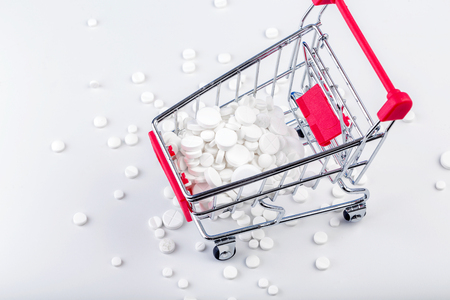Bunch of white pills with shopping cart. Scattered pills.の写真素材