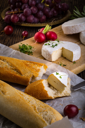 Cheese with white mold. Camembert or brie type. Radish, grapes and baguette. Healthy breakfast.の写真素材