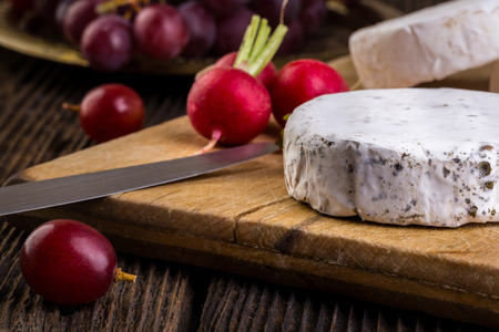 Cheese with white mold. Camembert or brie type. Radish and grapes. Healthy breakfast.の写真素材