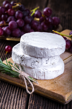 Cheese with white mold. Camembert or brie type. Grape and branch of rosemary. Healthy breakfast.の写真素材