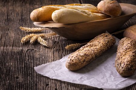 Fresh cereal pastry. Freshly baked white and brown baguette with wheat ears and grain.の写真素材