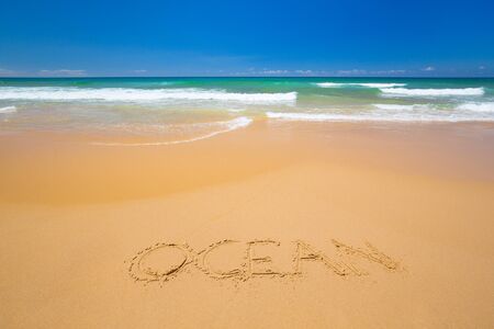 Nice open beach with inscription in sand. Ocean in the background on the sunny day.の写真素材